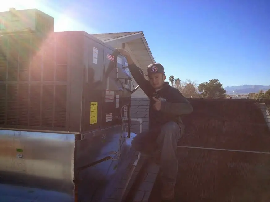 HVAC technician performing AC Tune-Up on a rooftop unit in Cortland